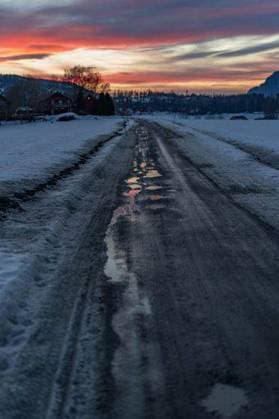 A vertical shot of a country road with puddles in winter at sunset. 17193631 RECORD DATE NOT STATED