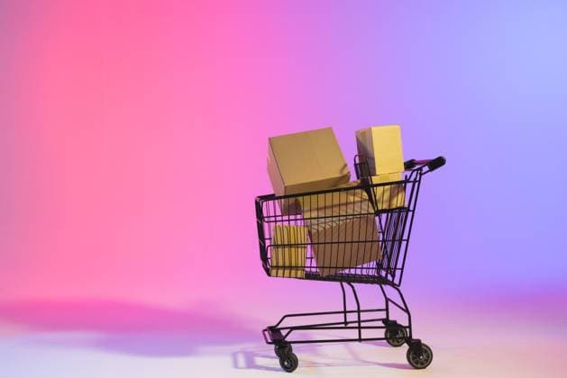 Shopping trolley with boxes and copy space over neon purple background. Cyber monday, black friday, online shopping, shipping and global connections concept.
