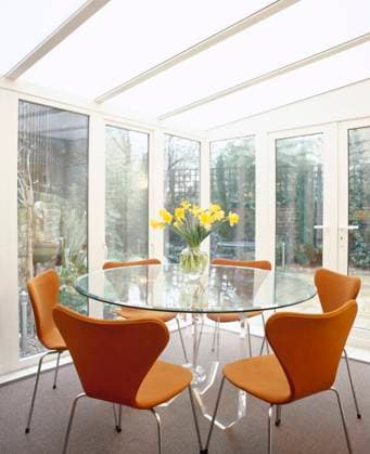 Modern conservatory dining area with glass walls and roof, round glass table, an Modern conservatory dining area with glass walls and roof, round glass table, and butterfly-back chairs., Credit:Grant Govier Avalon  Copyright: xGrantxGovierx xAvalonx 0512760510