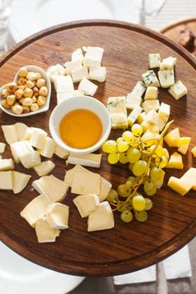 Cheese plate with hazelnuts, honey, grapes on wooden table Cheese plate with hazelnuts, honey, grapes on wooden table on the served table Copyright: xZoonar.com OksanaxShufrychx 13194420
