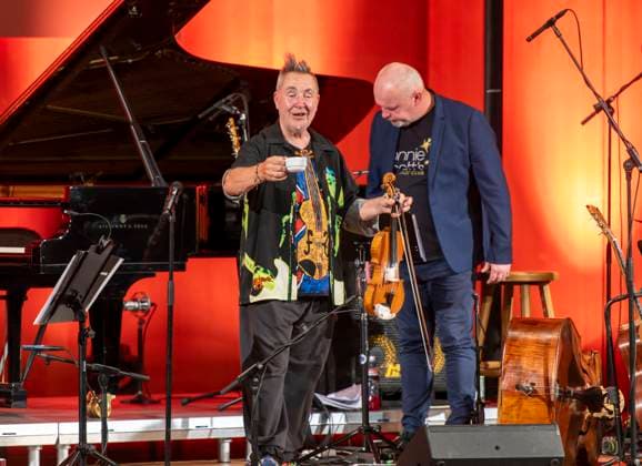 27.09.2023, Internationales Klassikfestival: Festival der Nationen 2023, im Kurhaus Bad Wörishofen im Unterallgäu, Der britische Violinist Nigel Kennedy & friends, Kennedy mit Kaffee-Tasse auf der Bühne nach der Pause. 27.09.2023, Klassikfestival Bad Wörishofen 27.09.2023, Klassikfestival Bad Wörishofen