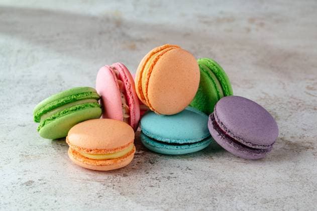 multicolored macaroon cookies lie on a white kitchen table R_KUAL2310017C-1254979-01
