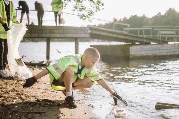 Creative Highlights Symbolbilder Full length of boy crouching while reaching for plastic at lakeshore Sweden, Stockholm, model released Copyright: xMaskotx , MA103765 MA103765