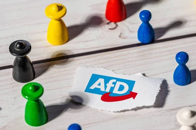 5 October 2023: Colorful wooden figures around a sign with AfD Alternative for Germany logo. Politics Icon Image PHOTO MONTAGE *** Bunte Holzfiguren um ein Schild mit AfD Alternative für Deutschland Logo. Politik Symbolbild FOTOMONTAGE