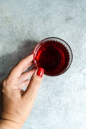 Top view of cropped unrecognizable hands of woman holding transparent glass of traditional saperavi Georgian red wine served in clean concrete gray background table Model Released AnnaBogush_ID16895_516072_005 Copyright: xAnnaxBogushx