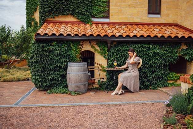 Creative Highlights Symbolbilder Young woman in elegant dress and straw hat sits at table on terrace of house. Young woman in elegant dress and straw hat sits at table on terrace of house. Beautiful girl with glass of ice orange cocktail in garden. Brick walls covered with ivy, flowers, trees and wooden barrel ,model released, Symbolfoto Copyright: xZoonar.com DashaxPetrenkox 20530005 ,model released, Symbolfoto ,property released