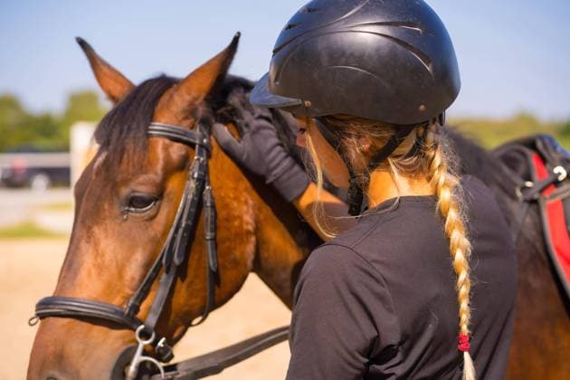 IMAGO Creative, Kinder auf dem Reiterhof Kaukasisches blondes Mädchen auf einem Pferd, das ein braunes Pferd streichelt und verwöhnt, gekleidet in einen schwarzen Reiter mit Sicherheitshut *** Kaukasisches Blondes Girls at a Horse, the a brown Horse strokes and spoiled, dressed in a Black people Reiter with Safety hat Copyright: imageBROKER/UnaixHuizi ibxuhu09694956.jpg ,model released, Symbolfoto ,property released