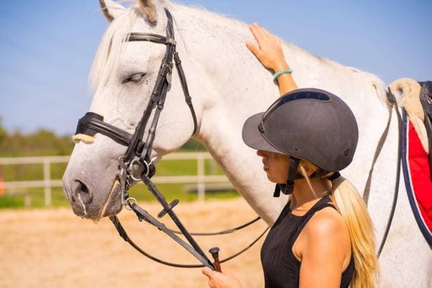 IMAGO Creative, Kinder auf dem Reiterhof Kaukasisches blondes Mädchen streichelt ein weißes Pferd beim Reiten, gekleidet in einen schwarzen Reiter mit Sicherheitshut *** Kaukasisches Blondes Girls strokes a White Horse at Riding, dressed in a Black people Reiter with Safety hat Copyright: imageBROKER/UnaixHuizi ibxuhu09694982.jpg ,model released, Symbolfoto ,property released