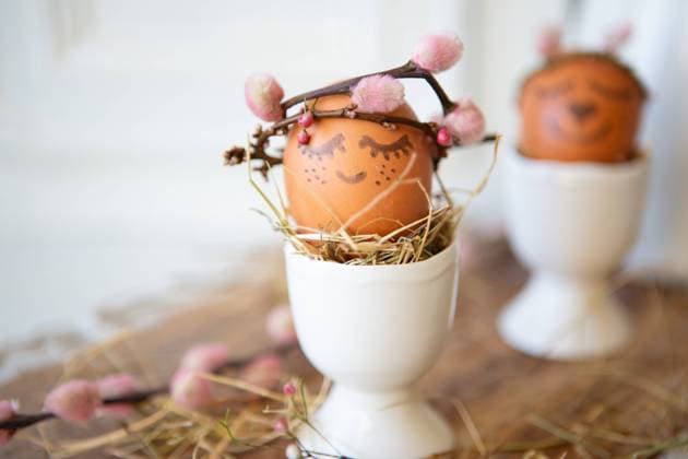 8 February 2023: Easter egg in egg cup with crown of branches and face. Easter concept *** Osterei in Eierbecher mit Krone aus Zweigen und Gesicht. Ostern Konzept
