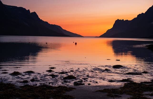 September 05, 2023: Sunset brings a lingering stillness and shades of autumn orange to a Norwegian fjord north of the Arctic Circle. Tromso, Norway. Tromso Norway - ZUMAc04_ 1035427968st Copyright: xLarryxClouse Csmx