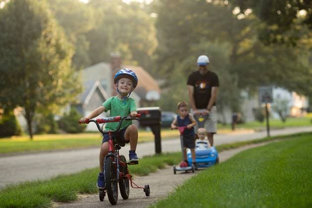 Two boys on bike and scooter; father pushes baby in a car, joyful United States, Connecticut, Southington CR_ASOG231010-1263429-01 ,model released, Symbolfoto