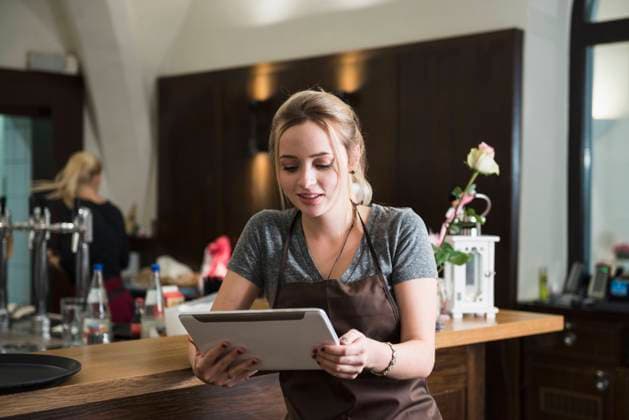 Young woman in apron using tablet at restaurant Rosenheim, Rosenheim, Germany CR_EDDR161104-01080-01 ,model released, Symbolfoto ,property released