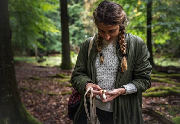 Woman With Long Braids Identifying Mushrooms In Scandinavia Denmark, Hareskovby CR_EMWIXA231011-1266575-01 ,model released, Symbolfoto