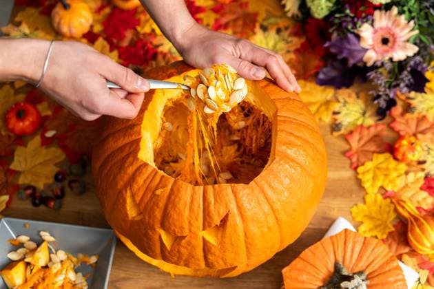 Augsburg, Bavaria, Germany - 17 October 2023: Hollowing out a Halloween pumpkin. Man hollows out a traditional Halloween pumpkin with a spoon and removes pulp and pumpkin seeds. DIY Decoration *** Aushöhlen von einem Halloween Kürbis. Mann höhlt mit einem Löffel einen traditionellen Halloween-Kürbis aus und entfernt Fruchtfleisch und Kürbiskerne. DIY Dekoration
