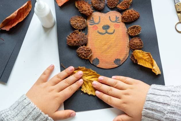 6 October 2023: Children s fun with autumn leaves: creative crafts at home. A child makes a collage of a hedgehog. Hands glue leaves and chestnut shells from the picture *** Kinderspaß mit Herbstlaub: Kreatives Basteln zu Hause. Ein Kind bastelt eine Kollage von einem Igel. Hände kleben Laub und Kastanien Schalen aus das Bild