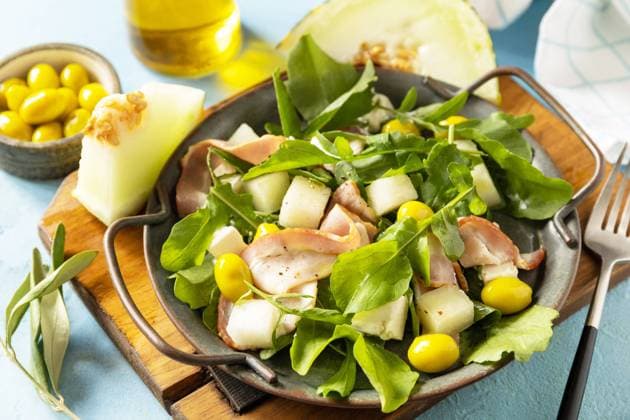 Traditional Spanish and Italian appetizer. Summer mediterranean salad with melon, bacon, olives, white cheese and arugula on blue stone background. Traditional Spanish and Italian appetizer. Summer mediterranean salad with melon, bacon, olives, white cheese and arugula on blue stone background. Copyright: xZoonar.com ELENAxHRAMOVAx 20552258