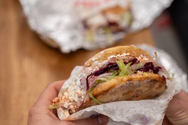 IMAGO Creative, Food, Fast Food, Döner Ein Mann hält einen vegetarischen Döner Kebap ohne Fleisch in der Hand. Auf dem Esstisch Aluminium Folie von der Verpackung. Fastfood to Go