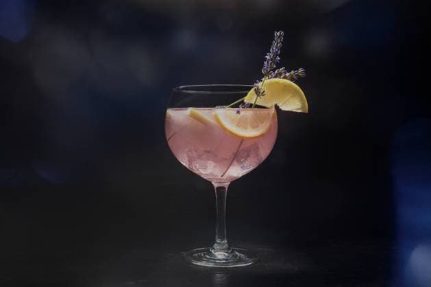 Fancy cocktail with fresh fruit. Gin and tonic drink with ice at a party Fancy cocktail with fresh fruit. Gin and tonic drink with ice at a party, on a black background. Alcohol with lavender and lemon, toned image Copyright: xZoonar.com KaterinaxSolovyevax 20580098