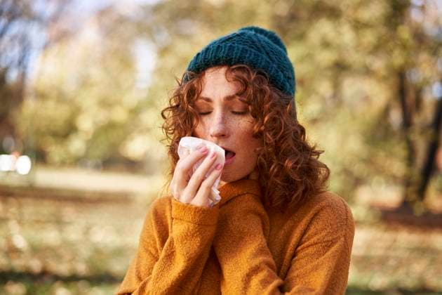 Redhead woman sneezing at autumn park model released, Symbolfoto, ABIF02065