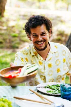 Smiling man offering food at picnic table in garden model released, Symbolfoto, EBSF03751