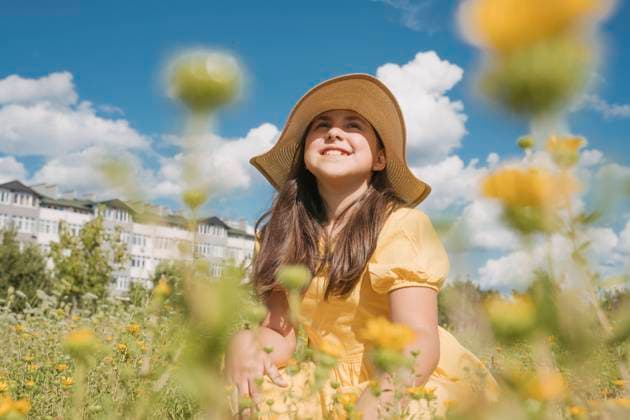 Contemplative girl wearing hat in flower field on sunny day model released, Symbolfoto, OSF01975