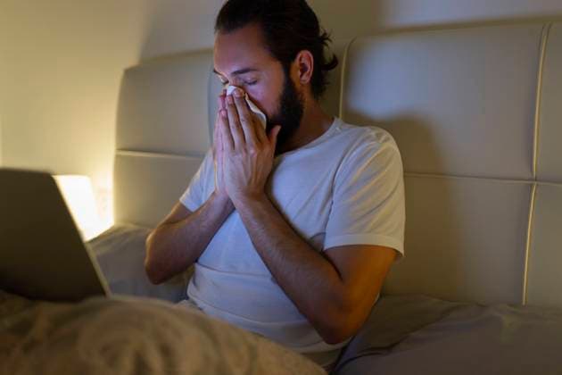 Man blowing nose and sitting with laptop on bed model released, Symbolfoto property released, JPTF01322