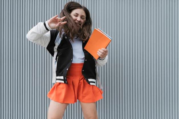 Smiling schoolgirl showing peace sign and holding books in front of wall model released, Symbolfoto, OSF02137