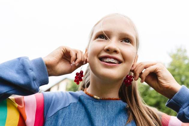 Smiling girl holding fresh redcurrants near ears model released, Symbolfoto, EYAF02846