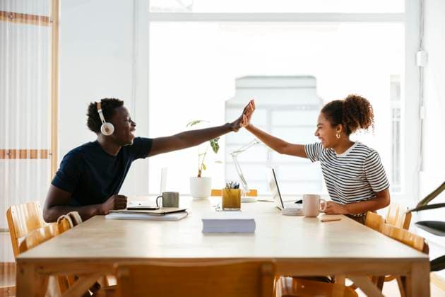 Tschechien, Hochschule streicht wegen KI und Plagiate Bachelorarbeiten Happy young students giving high-five to each other at desk model released, Symbolfoto property released, EBSF03880