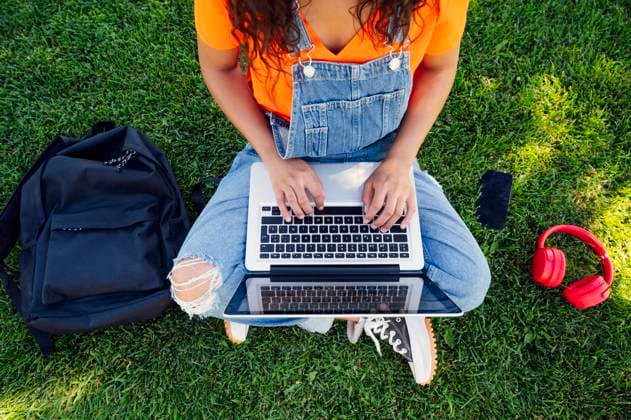 Tschechien, Hochschule streicht wegen KI und Plagiate Bachelorarbeiten Young student sitting on grass and using laptop in campus model released, Symbolfoto, PGF01718