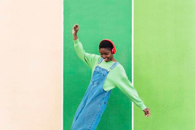 Happy young woman dancing and having fun in front of multi colored wall model released, Symbolfoto, PNAF05819