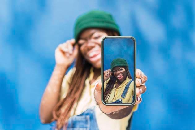 Happy young woman photographing through smart phone model released, Symbolfoto property released, PNAF06049