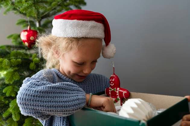 Girl wearing Santa hat holding box of Christmas decorations at home model released, Symbolfoto property released, SVKF01623