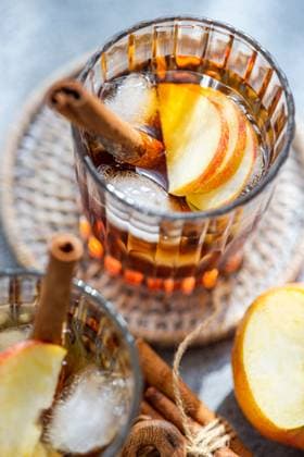 Top view of fresh apple cider cocktails garnished with cinnamon sticks, star anise, and apple slices in a crystal glass filled with ice cubes on a textured background Model Released AnnaBogush_ID17232_524319_003 Copyright: xAnnaxBogushx RECORD DATE NOT STATED