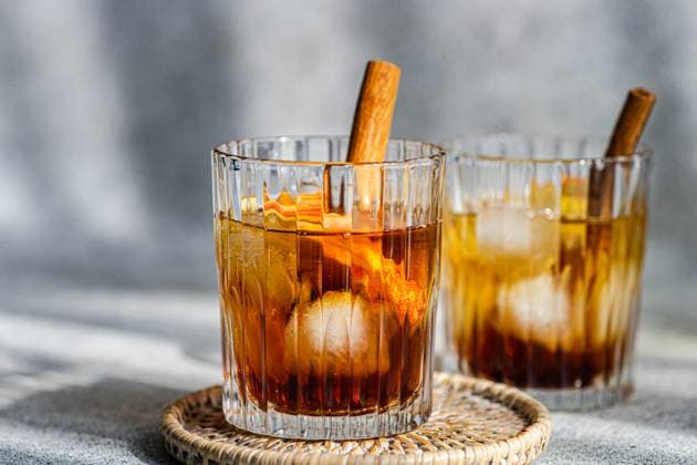 Fresh apple cider cocktails garnished with cinnamon sticks, star anise, and apple slices in a crystal glass filled with ice cubes on a textured background Model Released AnnaBogush_ID17232_524323_007 Copyright: xAnnaxBogushx