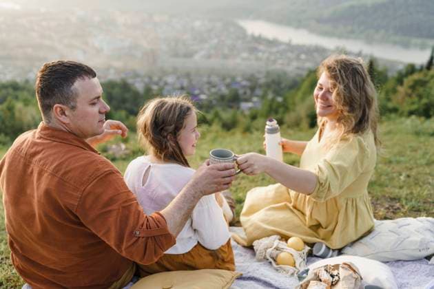 IMAGO Creative, Ostern, Bräuche, Osterspaziergang Happy woman serving tea to man sitting with daughter model released, Symbolfoto, VBUF00396