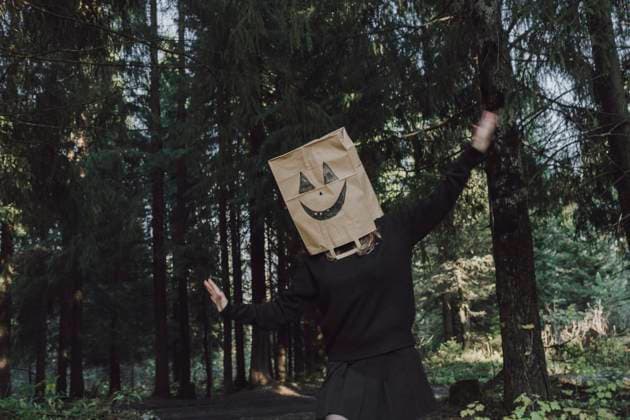 Carefree woman wearing paper bag over face and dancing in forest model released, Symbolfoto, VBUF00454