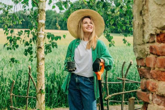 Smiling woman holding potted plant in garden model released, Symbolfoto, VSNF01129