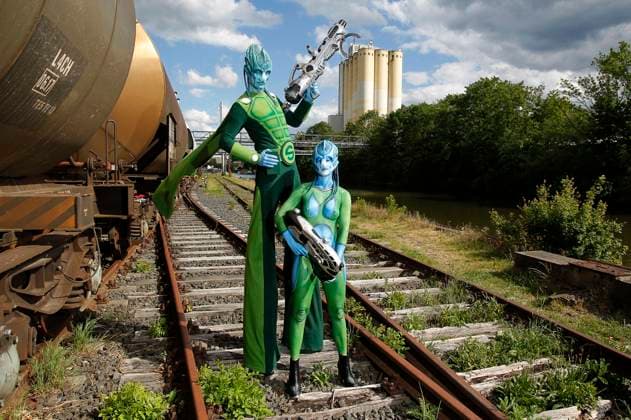 Aus dem FARBKÖRPER Kalender 2024 - Geek Art-Bodypainting und Transformaking: Aliens besuchen die Erde mit Barbara und Enrico als Besucher zwischen abgestellten Eisenbahnwaggons an der Weser in Hameln. Ein Projekt des Fotografen Tschiponnique Skupin und des Bodypainters und Transformakers Enrico Lein