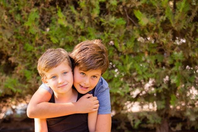 Two brothers. Family photo Two wonderful boys are hugging. The older brother has brown hair and green eyes, the younger brother is blond with blue eyes. Warm spring day in a green park. ,model released, Symbolfoto Copyright: xZoonar.com kavramx 20621759 ,model released, Symbolfoto ,property released