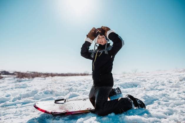 Preteen boy kneels in snow with sledding board while adjusting g Bismarck, North Dakota, United States CR_KIFR231105C-149053-01 ,model released, Symbolfoto