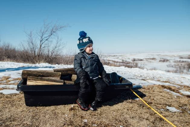 Side view of small boy sitting on sled full of firewood in snowy Bismarck, North Dakota, United States CR_KIFR231105C-149060-01 ,model released, Symbolfoto