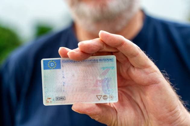 Augsburg, Bayern, Deutschland - 27 Oktober 2023: Ein alter Mann mit Bart hält einen Füherschein in der Hand. Fahrtauglichkeit im Alter Konzept FOTOMONTAGE *** An old man with a beard holds a driver s license in his hand. Driving fitness in old age concept PHOTOMONTAGE