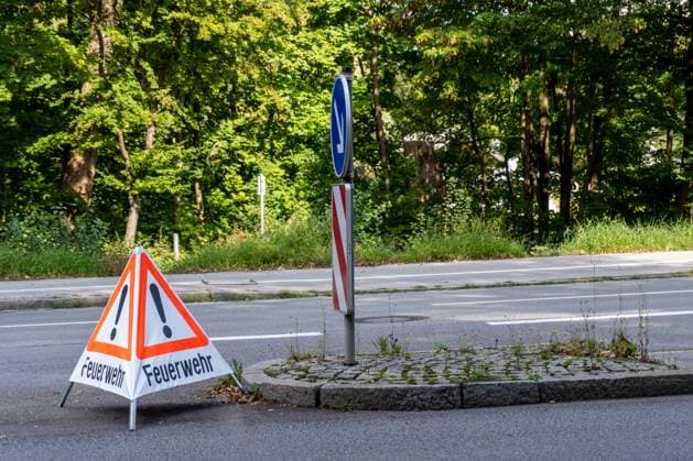 Feuerwehr und Notarzt, Symbolfotos Augsburg, Bayern, Deutschland - 24 September 2023: Ein dreieckiges Warnschild am Straßenrand. Das Schild ist orange mit einem weißen Rand und trägt die Worte Feuerwehr. Warnung vor einem Feuerwehreinsatz *** A triangular warning sign on the side of the road. The sign is orange with a white border and bears the words Feuerwehr. Warning of a fire department operation