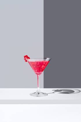 Glass filled with red pomegranate cocktails served with pomegranate seeds against a gray backdrop, casting a soft shadow Model Released RuthCarrodeguas_ID17356_527890_005 Copyright: xRuthxCarrodeguasx RECORD DATE NOT STATED