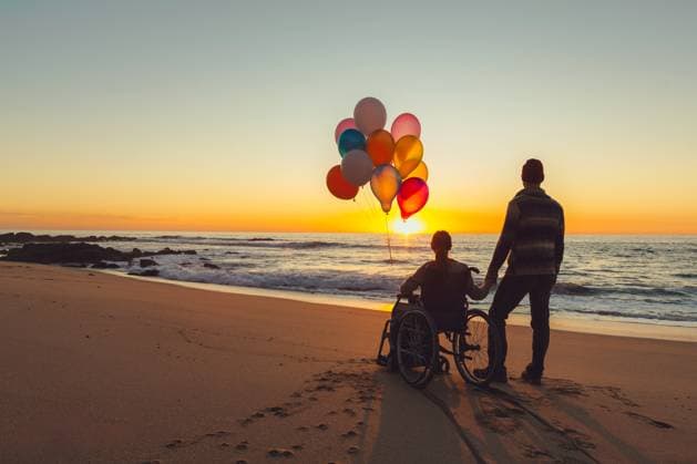 Creative Highlights Symbolbilder Couple on the beach with woman on a wheelchair holding balloons Peniche, Portugal, Leiria District, Portugal R_ERRE220317-951954-01 ,model released, Symbolfoto