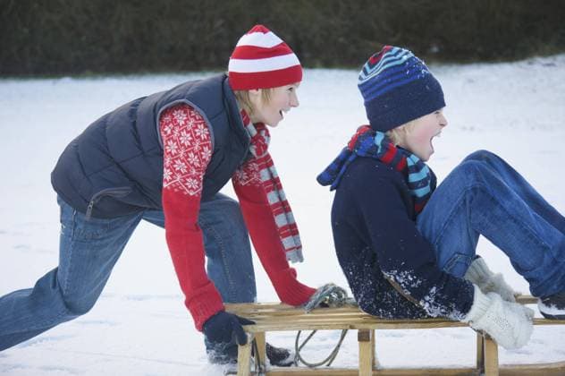 Profile of a boy pushing a friend sitting on a sled United Kingdom  Copyright: JuttaxKlee fStopImages2045201 ,model released, Symbolfoto