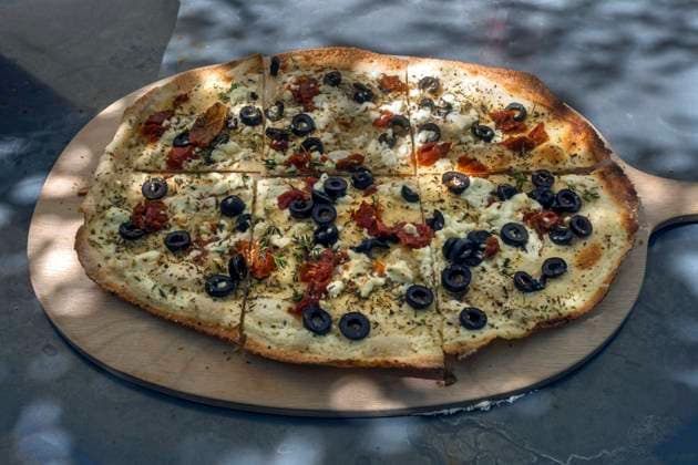 Flammkuchen mit getrockneten Tomaten, Schafskäse, Oliven und Schnittlauch auf einem Holzbrett serviert, Bayern, Deutschland, Europa *** Flambé with dried Tomatoes, Sheeps cheese, Olives and Chives at a Wooden board served, Bavaria, Germany, Europe Copyright: imageBROKER HelmutxMeyerxzurxCapellen iblmzc09837998.jpg