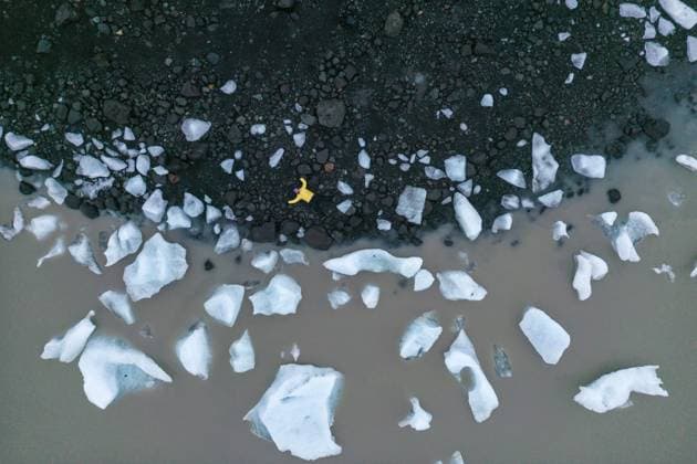 Creative Highlights Symbolbilder From below featuring person in yellow jacket lying down standing on volcanic black sand beach surrounded by scattered white ice chunks in Vatnajokull National Park, Iceland Model Released JuanLopez_ID17531_531467_005 Copyright: xJuanxLopezx RECORD DATE NOT STATED