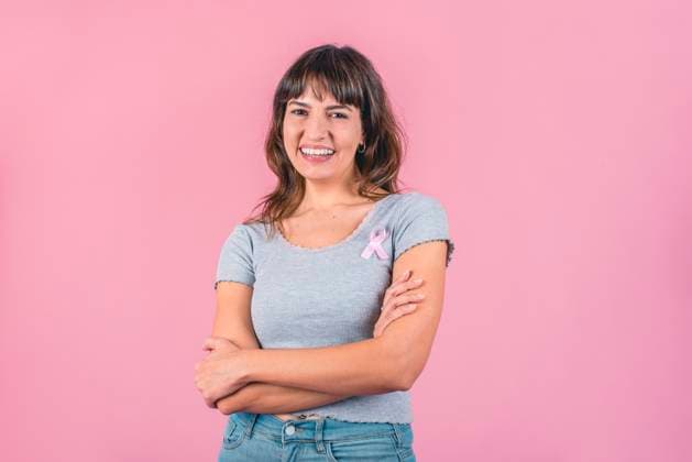 Happy woman wearing a pink breast cancer awareness ribbon while looking at camera Model Released ValeriaVenezia_ID16364_497848_010 Copyright: xValeriaxVeneziax RECORD DATE NOT STATED
